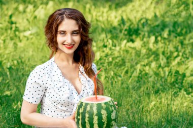 Karpuzlu güzel bir kadın çimlerin üzerinde oturur..