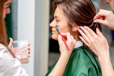 Makyaj ve kuaförden makyaj ve saç stili alan genç bir kadın..