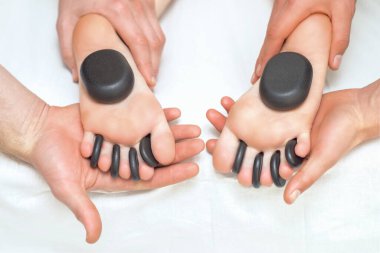 Masaj terapistleri ayaklarını tutarken kadının ayağında taşlar var..