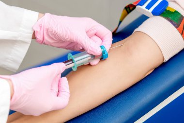 Hemşire, analizde kadın hastadan kan örneği alıyor..