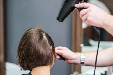 Profesyonel kuaför güzellik salonunda kadın saçını kurutuyor. Saç stilistinin kolları kapalı kadın saçlarını kurutur. Saç stili ve insanlar konsepti.