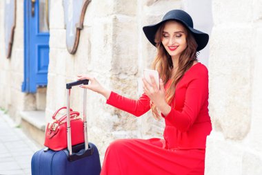 Siyah şapkalı hoş bir gezgin caddedeki akıllı telefona bakıyor. Seyahat kavramı.