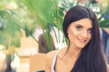 Doğa arka planında gülümseyen güzel esmer kadın portresi. Dışarıda uzun saçlı bir kız. Kapatın..