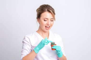 Güzellik uzmanı beyaz arka planda kaktüse dokunuyor. Tüy dökümü, şekerleme, epilasyon ve tüylerin alınması kavramı.