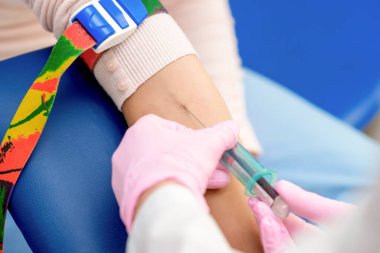 Hemşire kan örneği alır ve kadının koluna iğne batırır..