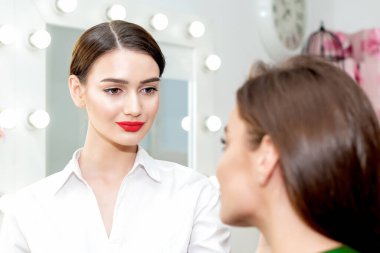 Makyöz, genç bir kadın için profesyonel makyaj yapıyor. Makyöz, müşteriyle çalışmaya hazır..