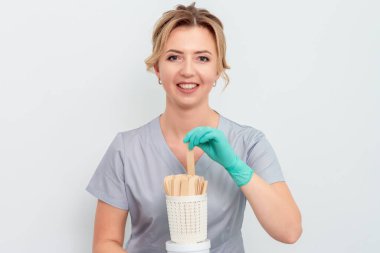 Ağda yapmak veya beyaz arkaplanda şekerleme yapmak için çubuk tutan güzellik uzmanı, boşluğu kopyala.