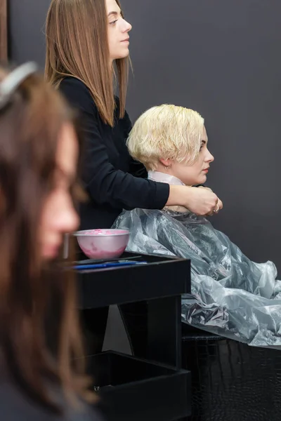理发师在给客人染发的时候用塑料布盖住他的客人 — 图库照片
