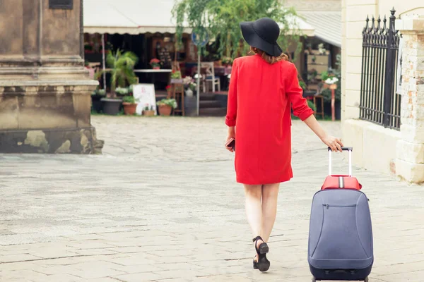 모자를 여성의 뒷모습 거리에서 가방을 잡아당기고 도시의 걷다가 여행하는 — 스톡 사진