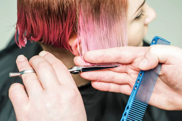 用剪刀剪掉粉红的头发是一只阳刚的手的特写 把注意力集中在手和头发上 理发师的手剪头发 — 图库照片