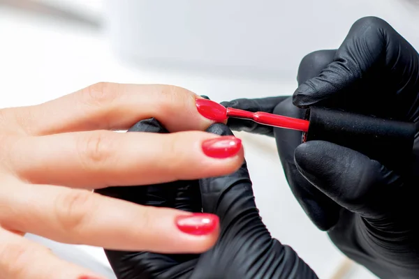 Manicurist Målar Naglar Med Röda Nagellack Salong Närbild — Stockfoto