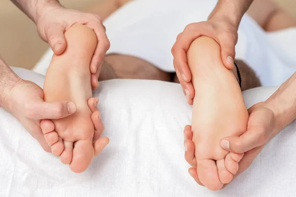 リラックスマッサージ上の人間の足の女性で4手を閉じる — ストック写真