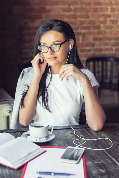Hermosa Mujer Gafas Está Escuchando Música Por Teléfono Inteligente Cafetería — Foto de Stock
