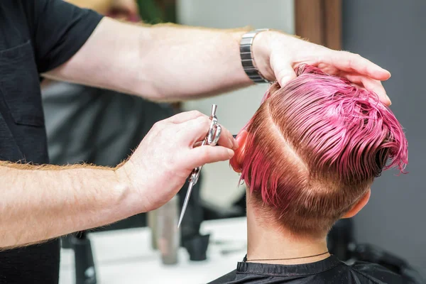 理发师正在为年轻女子剪着粉色的头发 她的头发是湿粉色的 后视镜也很近 — 图库照片