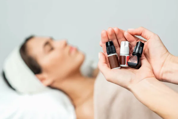 Close up of Little tubes with glue for eyelash extension in woman\'s hands on background of woman.