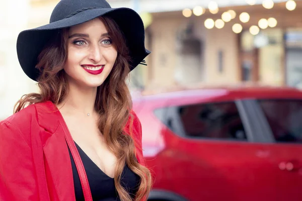 美しい笑顔若い女性で黒の帽子の背景に赤い車 — ストック写真