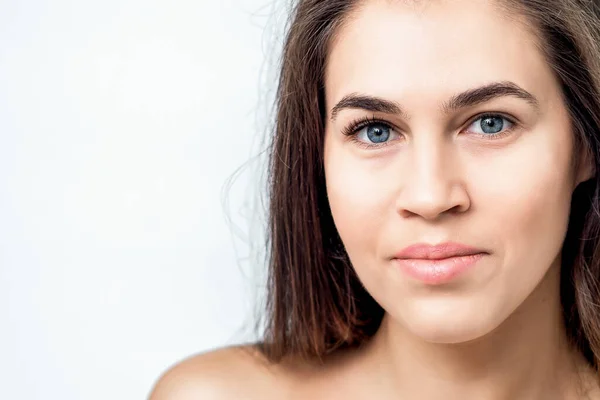 Portrait of beautiful young woman with natural makeup on her face on white background with copy space.