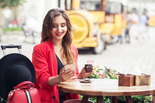 Sorrindo Viajante Menina Está Sentado Café Enquanto Olha Para Smartphone — Fotografia de Stock