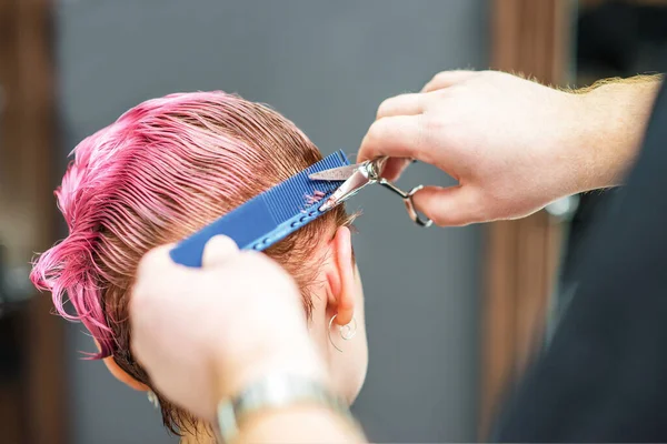 手の閉鎖は ヘアサロンで顧客の濡れたピンクの髪を切断しています 美容師は女性の髪をカットします 床手はピンクの髪をカット — ストック写真