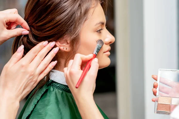 Makyaj ve kuaförden makyaj ve saç stili alan genç bir kadın..