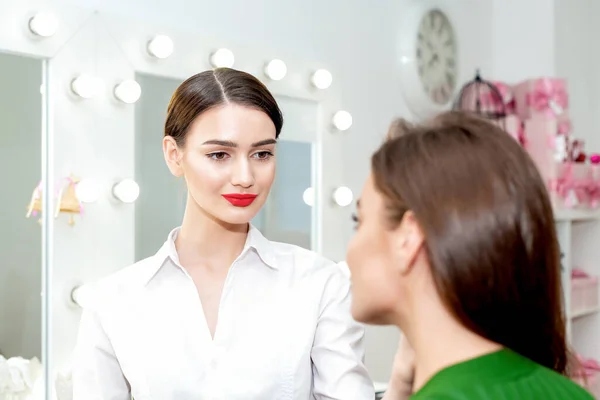 Makeup artist looks on client ready to work with client.