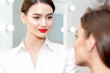 Makyaj sanatçısı genç bir kadın için profesyonel makyaj yapıyor. Makyaj sanatçısı bir müşteri üzerinde çalışmaya hazır..