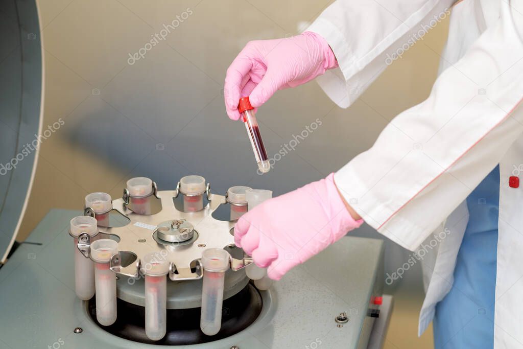 Doctor working with test tube of blood on centrifuge machine in medical clinic, analysis for coronavirus.