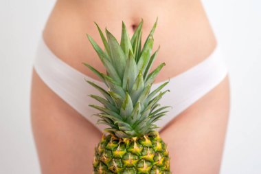 Beyaz kadın külotunun arka planında ananas yaprakları. Epilasyon, tüy dökümü ya da yakın hijyen kavramı.