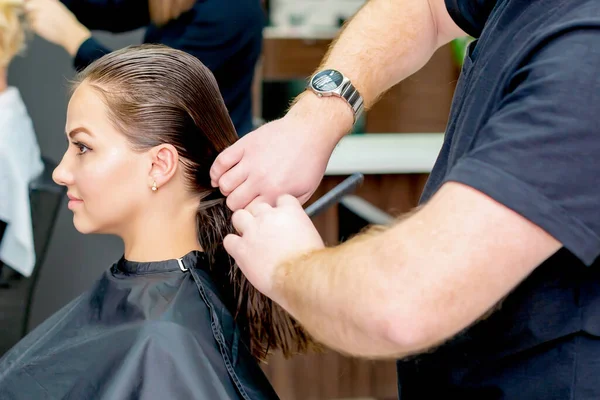 Woman receiving haircut closeup by hairdresser in hair salon.