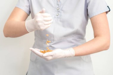 Balmumu fasulyeleri beyaz arka planda kozmetikçilere dağılıyor. Defilasyon ve epilasyon kavramı.