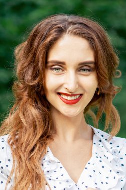 Yaz doğasının yeşil arka planında gülümseyen güzel bir kadının portresi..