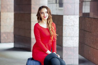 Güzel bir kadın bavula oturur ve kameraya bakar..