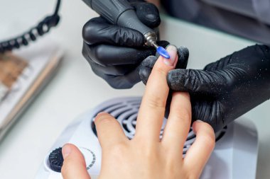 Manikür ustası özel elektrikli makineyle güzellik salonunda oje çıkarıyor..