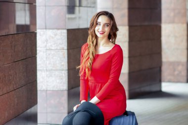 Güzel bir kadın bavula oturur ve kameraya bakar..