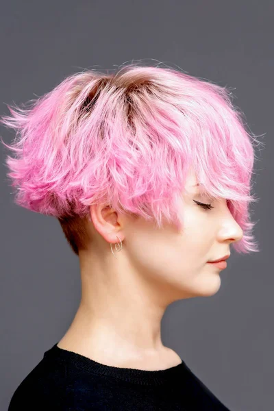 ピンクの髪型の女性はコピースペースとグレーの背景に閉じた目の側のビューで立つ — ストック写真