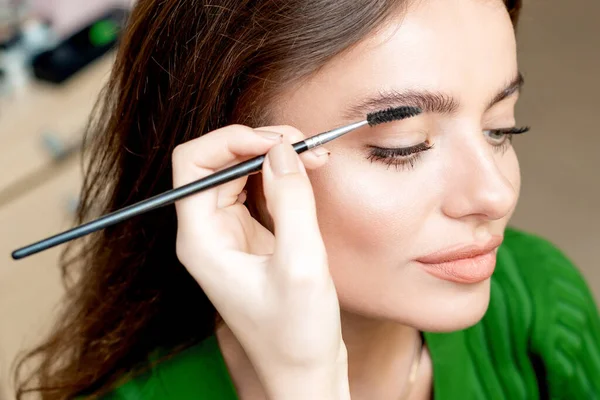 Makeup artist combs eyebrows with eyebrow brush tool copy space.