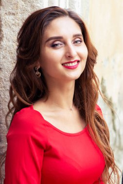 Güzel, gülümseyen bir kadının portresi eski duvarın üzerinde kırmızı elbise giyiyor..