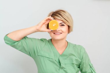 Kozmetik uzmanı, bir gözünü kapayan bir turuncu parçayı beyaz arka planda izole ediyor..