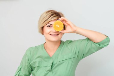 Kozmetik uzmanı, bir gözünü kapayan bir turuncu parçayı beyaz arka planda izole ediyor..