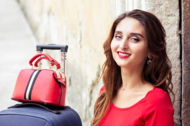 Güzel, gülümseyen bir kadının portresi kırmızı elbiseli, eski duvara gülümsüyor..