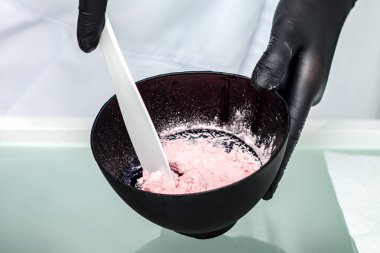 Kozmetik uzmanları siyah kasede aljinat maskesi hazırlıyorlar..