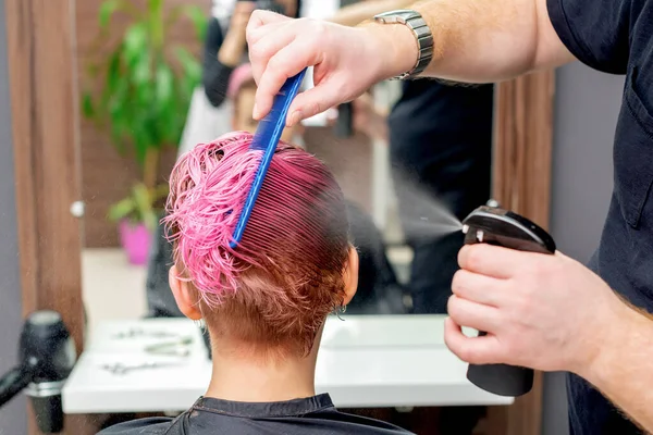 美容師の手はヘアサロンの女性のピンクの髪に水を振りかける — ストック写真