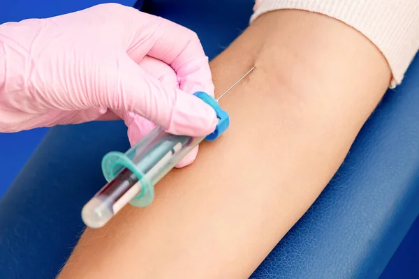 Nurse introducing the coronavirus vaccine introducing a needle into a vein of arm of woman.