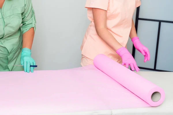 Kosmetologové Balí Růžové Jednorázové Prostěradlo Připravující Gauč Před Kosmetickým Zákrokem — Stock fotografie