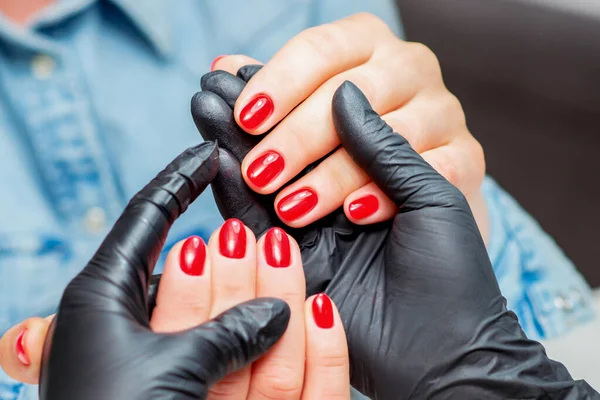 マニエリスムは近くに女性のクライアントの赤い爪で手を保持します — ストック写真