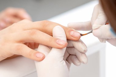 Manikür ustası elleri kadın tırnağına kadar pürüzsüz cilayı kapatıyor. Ellerin tırnaklarına dikkat et..