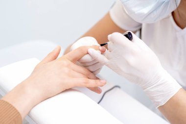 Manikür ustası elleri kadın tırnağına kadar pürüzsüz cilayı kapatıyor. Ellerin tırnaklarına dikkat et..