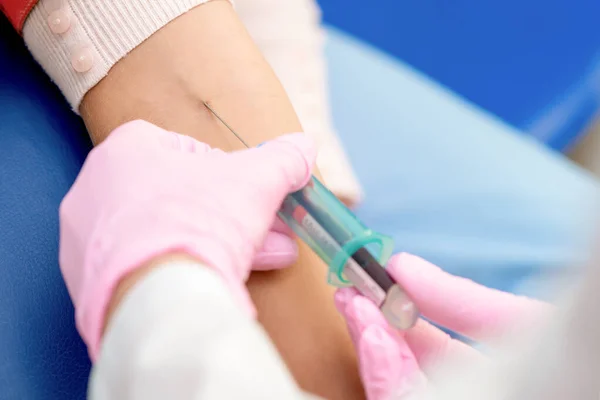 Nurse hands are introducing the coronavirus vaccine introducing a needle into a vein of arm of woman.
