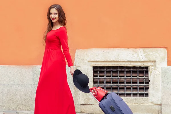 Kobieta Ciągnie Walizkę Czerwonej Długiej Sukience Ulicy — Zdjęcie stockowe