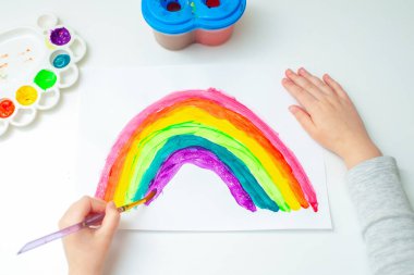 En tepedeki çocuk kağıdın üzerine suluboya çiziyor. Yaratıcılık kavramı.